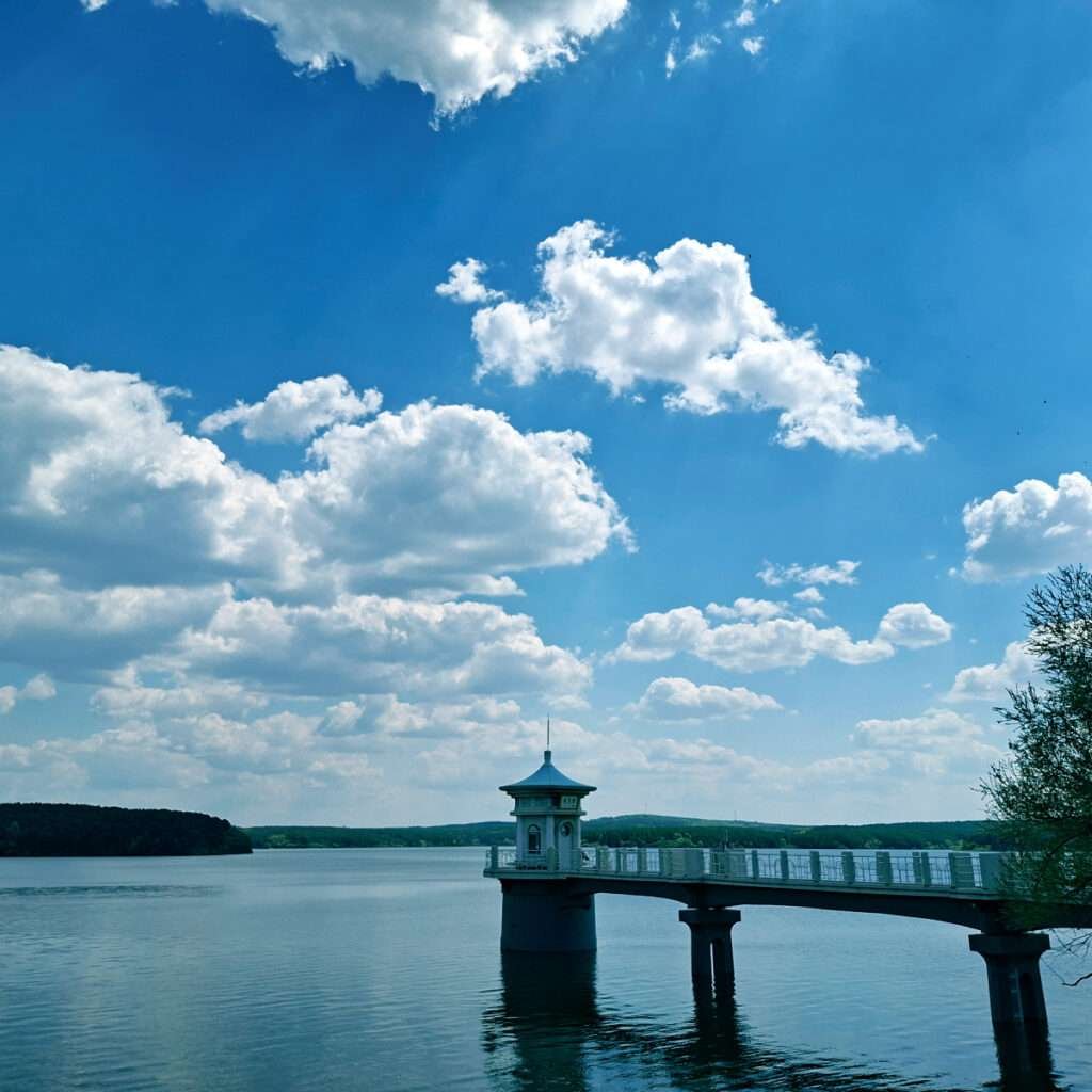 Bridge extending over calm lake to a small pagoda-roofed pavilion at its end